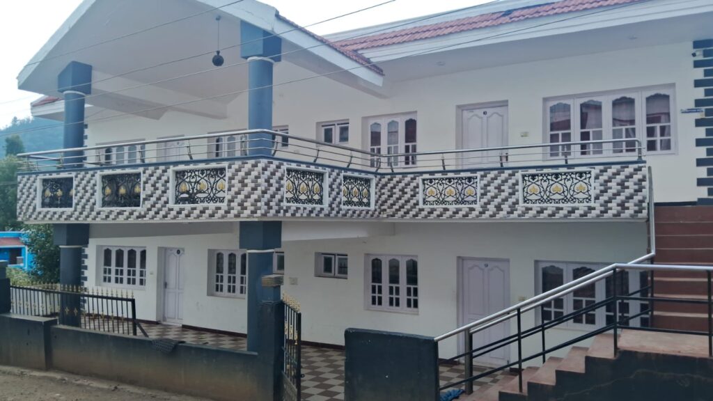 Two-story white cottage with balcony and staircase.