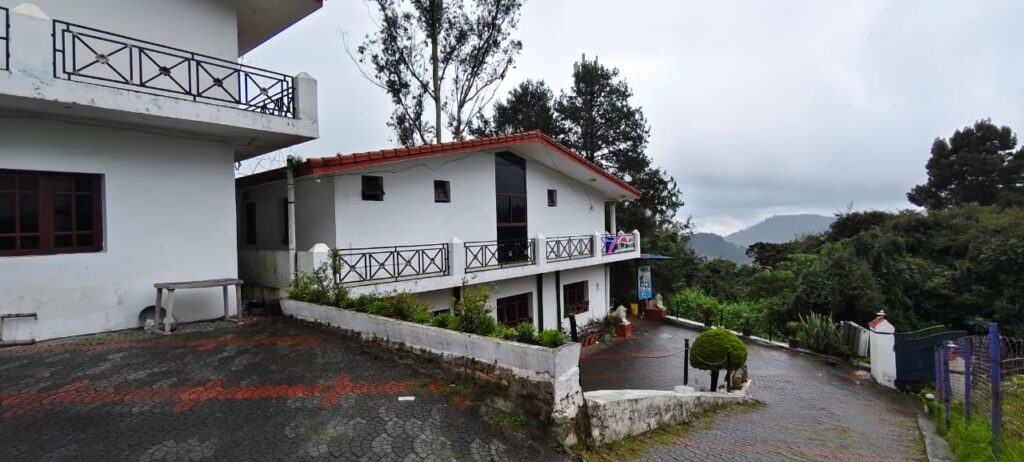 White hillside cottage in Ooty with balcony and mountain view