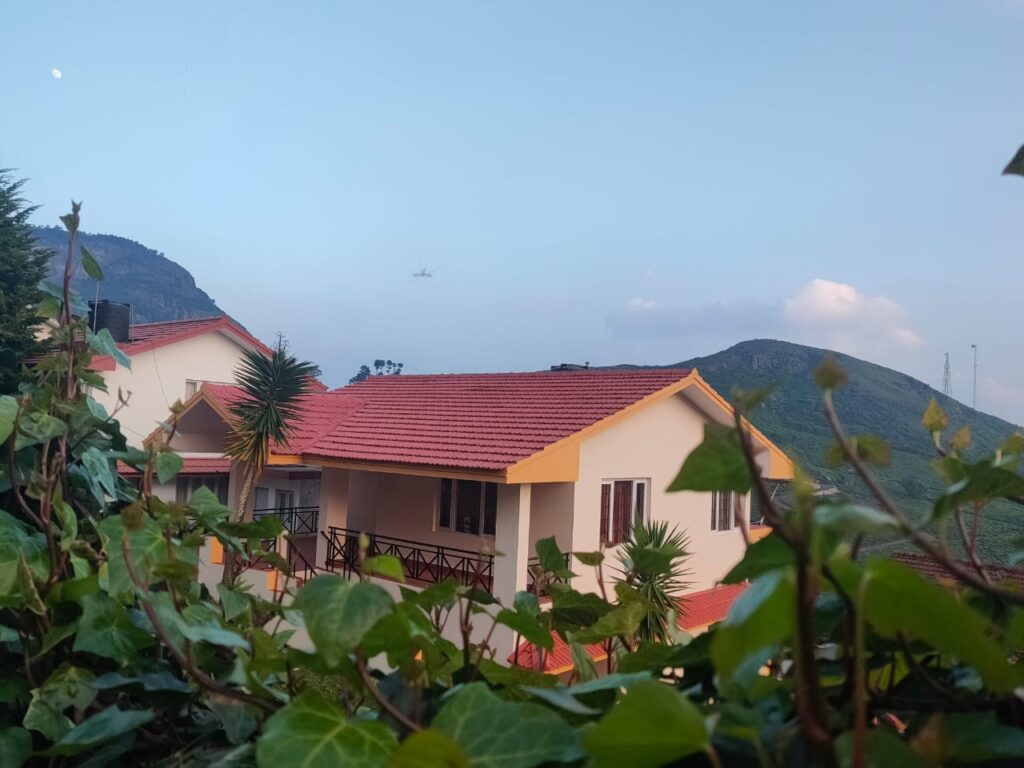 Scenic cottage in Ooty surrounded by lush greenery with red-tiled roofs and panoramic mountain views