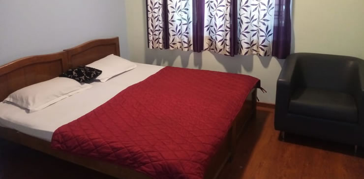 bedroom with double bed red blanket and chair