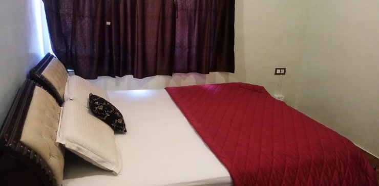 bedroom with red bedspread and dark curtains