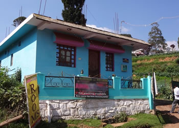 Ajmal Cottage exterior painted blue located along a scenic hill road