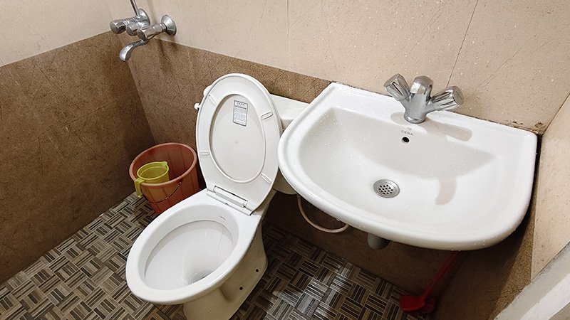 Bathroom with toilet, sink, and bucket