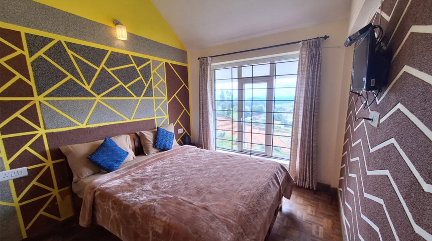Modern cottage bedroom with double bed and large window view in Ooty