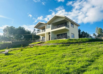 Cottage on a hill with lush green lawn under a bright blue sky