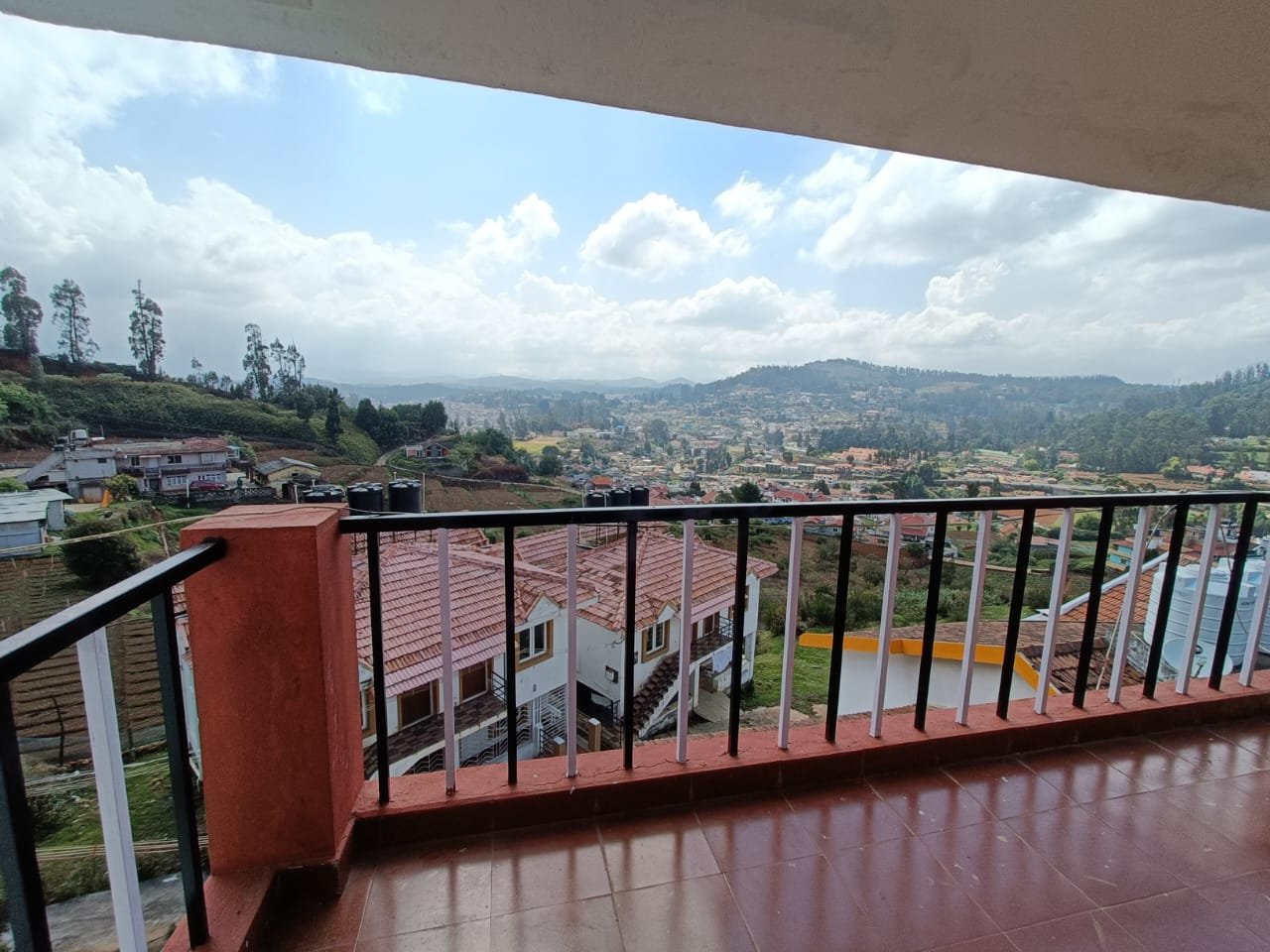 Daytime balcony view overlooking houses and hills