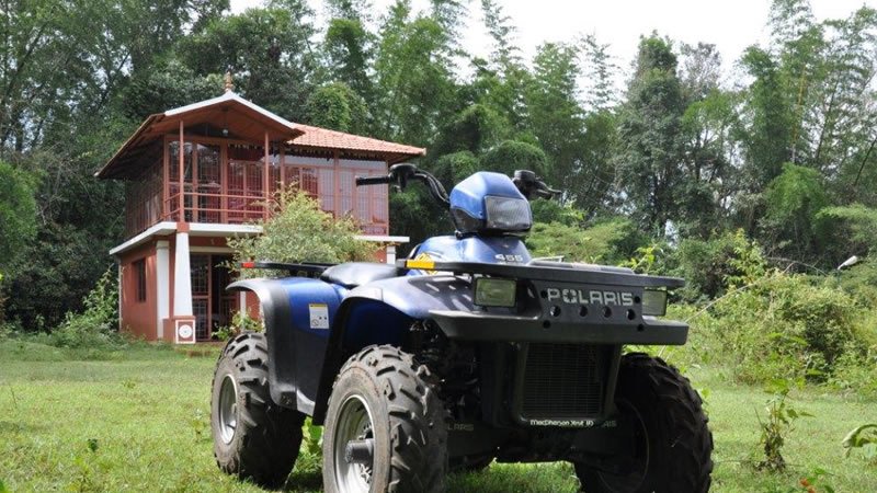 All-terrain vehicle parked on green grounds surrounded by trees near a holiday stay