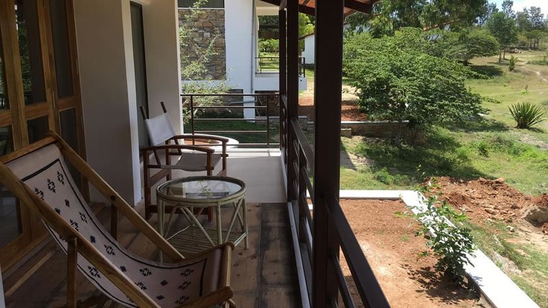 Private balcony with chairs and glass table overlooking green landscaped grounds