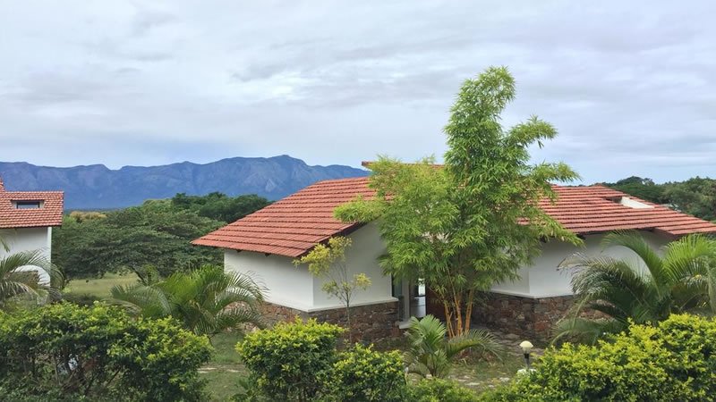 Holiday home with red tiled roof surrounded by landscaped greenery and mountain views