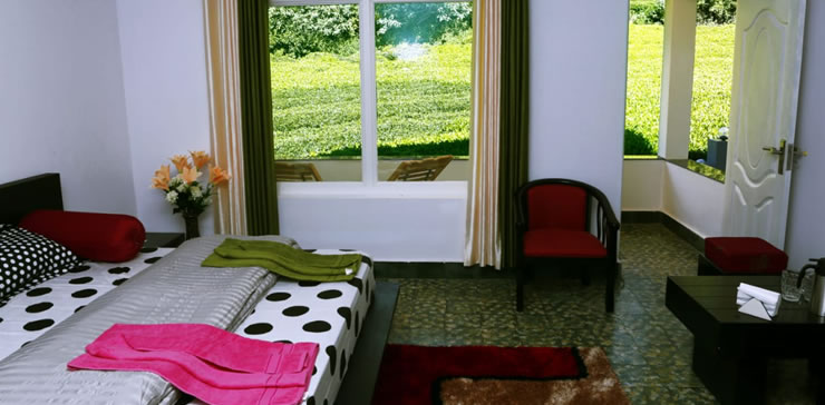 Spacious bedroom in Ooty estate cottage with a large window overlooking tea gardens