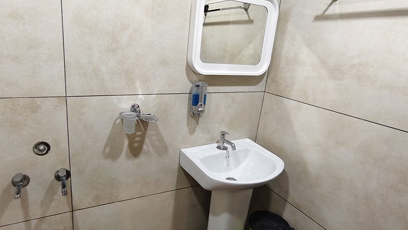 Clean bathroom interior with washbasin, wall mirror and tiled wall finish