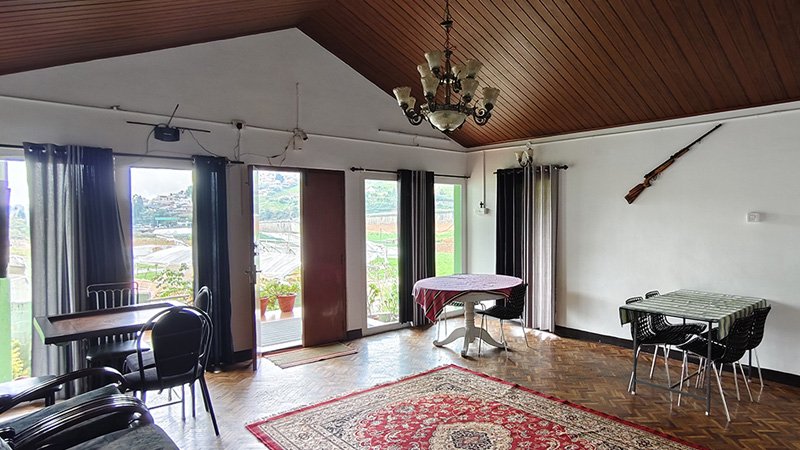 Spacious living hall with dining tables, seating area, chandelier lighting and large balcony doors