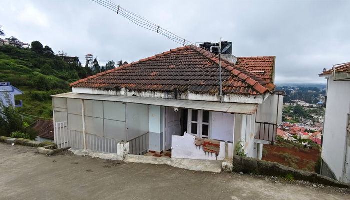 Mountain-side cottage in Ooty with cloudy sky and city view