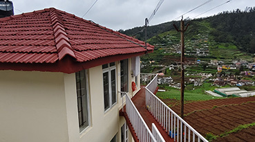 Cottage with red-tiled roof overlooking farmland and hills.