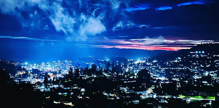 Night view of Ooty from Cottage View Point with glowing city lights and dramatic blue clouds