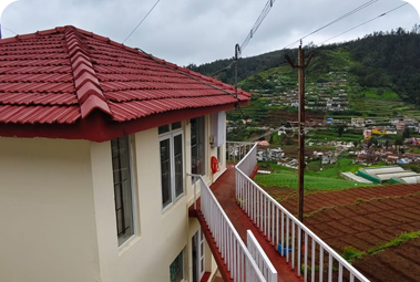Cottage with red tiled roof and balcony overlooking a green mountain valley