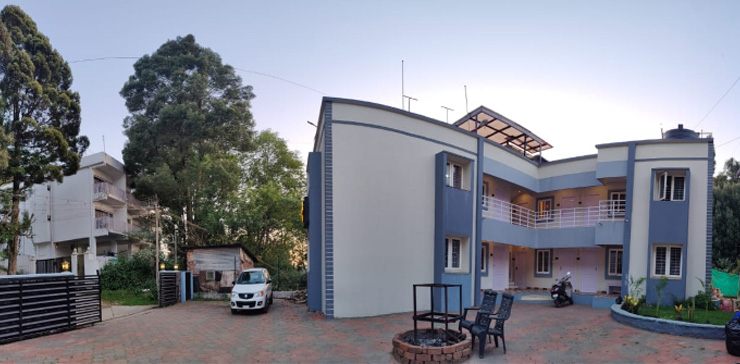 Front exterior view of HVN Cottage in Ooty with parking area and outdoor seating