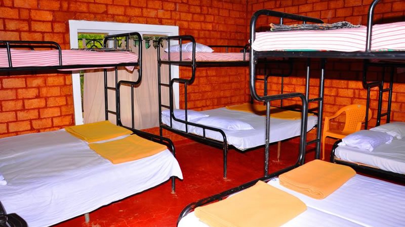 Group bedroom with multiple beds and metal bunk beds against red brick walls