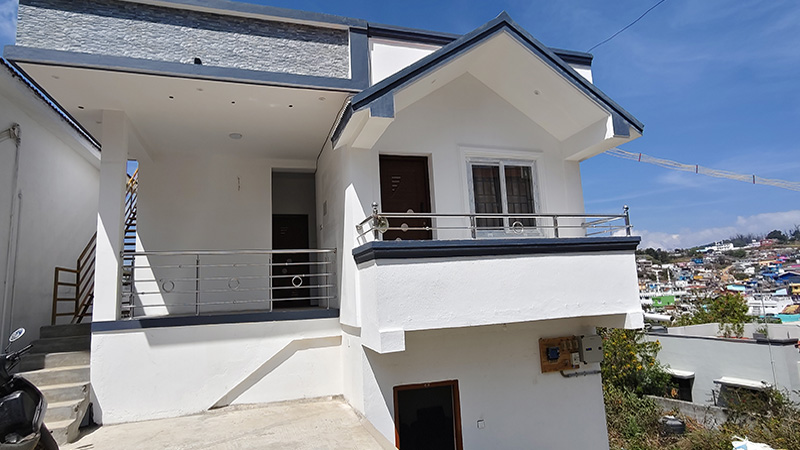 Exterior view of white cottage with balcony railing