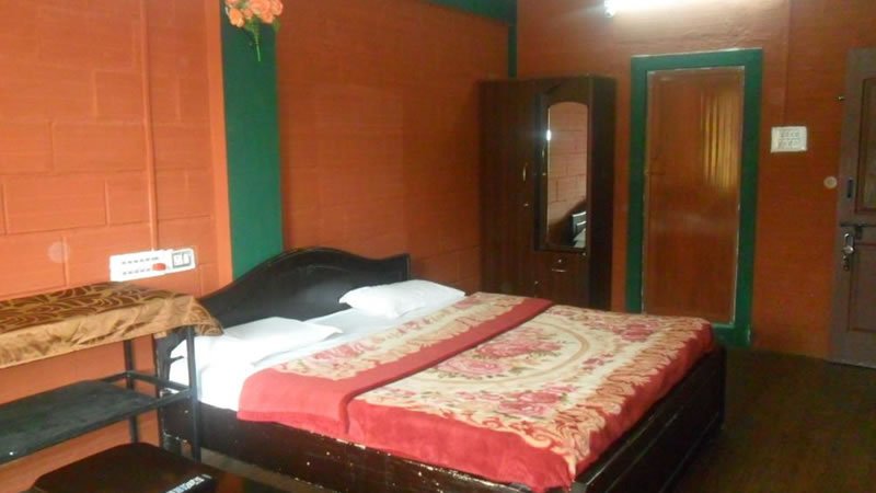 Double bedroom with wooden bed, red walls, wardrobe and simple furnishings