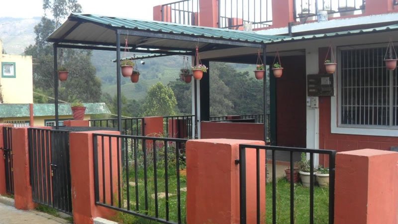 Holiday home exterior with covered veranda, hanging flower pots and fenced garden