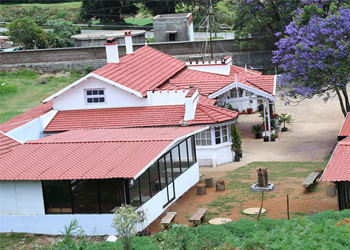 Exterior view of Nithy's Cottage, a peaceful hill-view homestay with red tiled roof and garden surroundings
