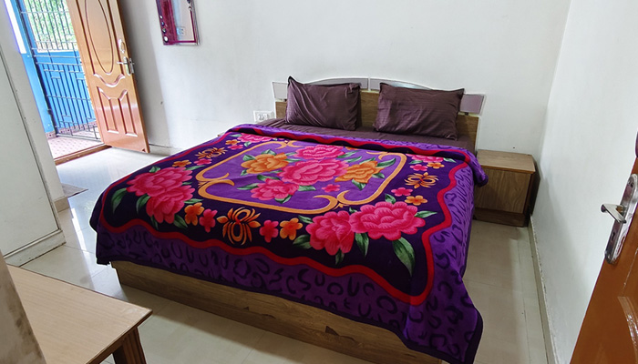 Ooty cottage bedroom with a neatly made single bed and floral blanket