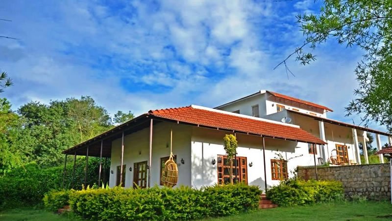 White hillside resort building surrounded by a green garden and trees