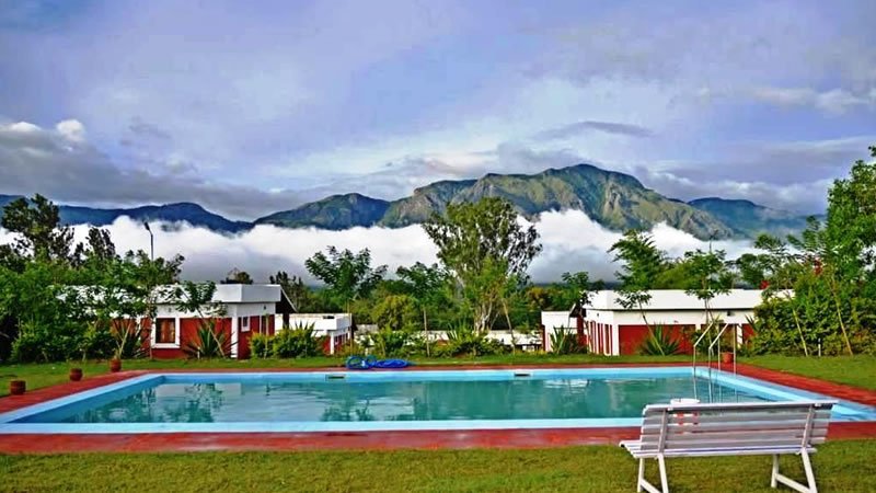Outdoor swimming pool surrounded by holiday homes with misty mountains behind