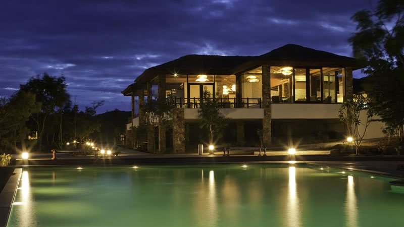 Resort swimming pool at night with illuminated building and outdoor lights