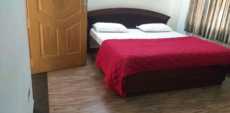 Comfortable bedroom at Toy Cottage with wooden bed and red bedspread
