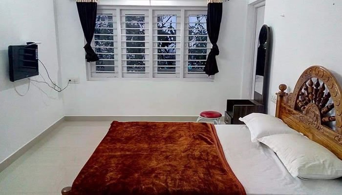 A cozy bedroom featuring a neatly made bed and a wall-mounted television
