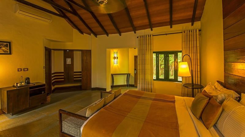 Spacious cottage bedroom with wooden ceiling, double bed and forest view