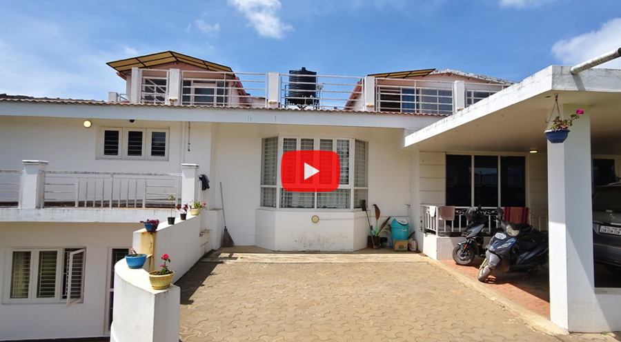 Front view of a white bungalow with parking area and balcony in Ooty